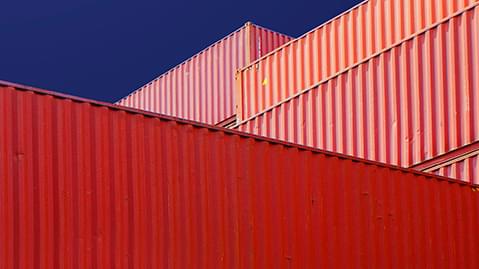 Close up of stacked red cargo containers against a blue background