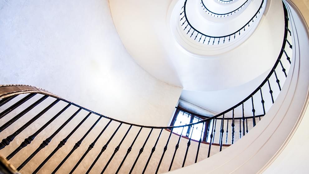 View up a spiral staircase with white walls and black railings