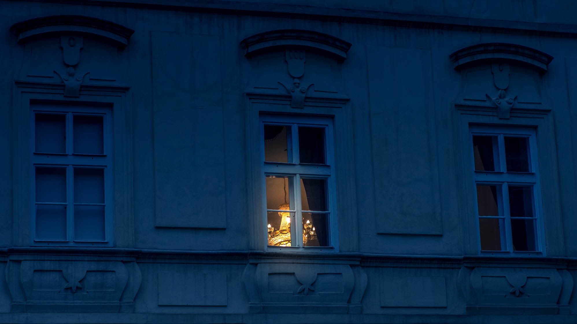 A photo of a window at night with a light shining through the window.