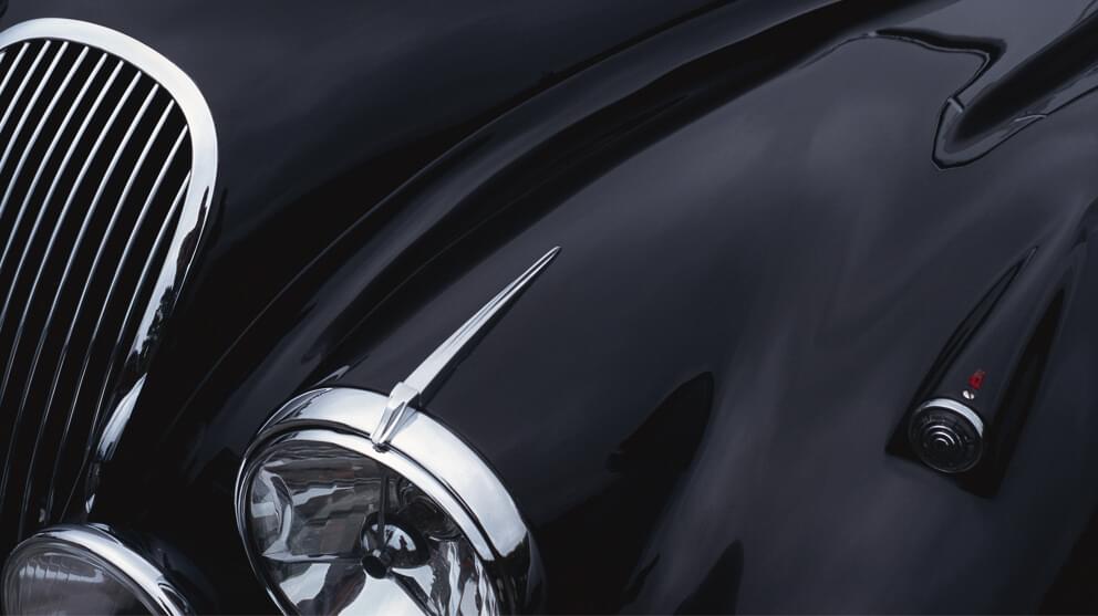 a black sports car hood showing a grill and headlight