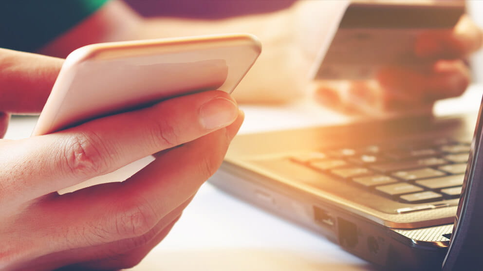 Smartphone and holding credit card with laptop